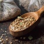 Seafood seasoning boil mixture in cheesecloth bags and a spoon scooped up with mustard seed salt bay leaves coriander and other slices showing