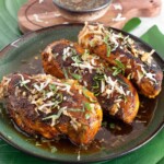 Thai grilled chicken on a plate sprinkled with fresh herbs and toasted coconut