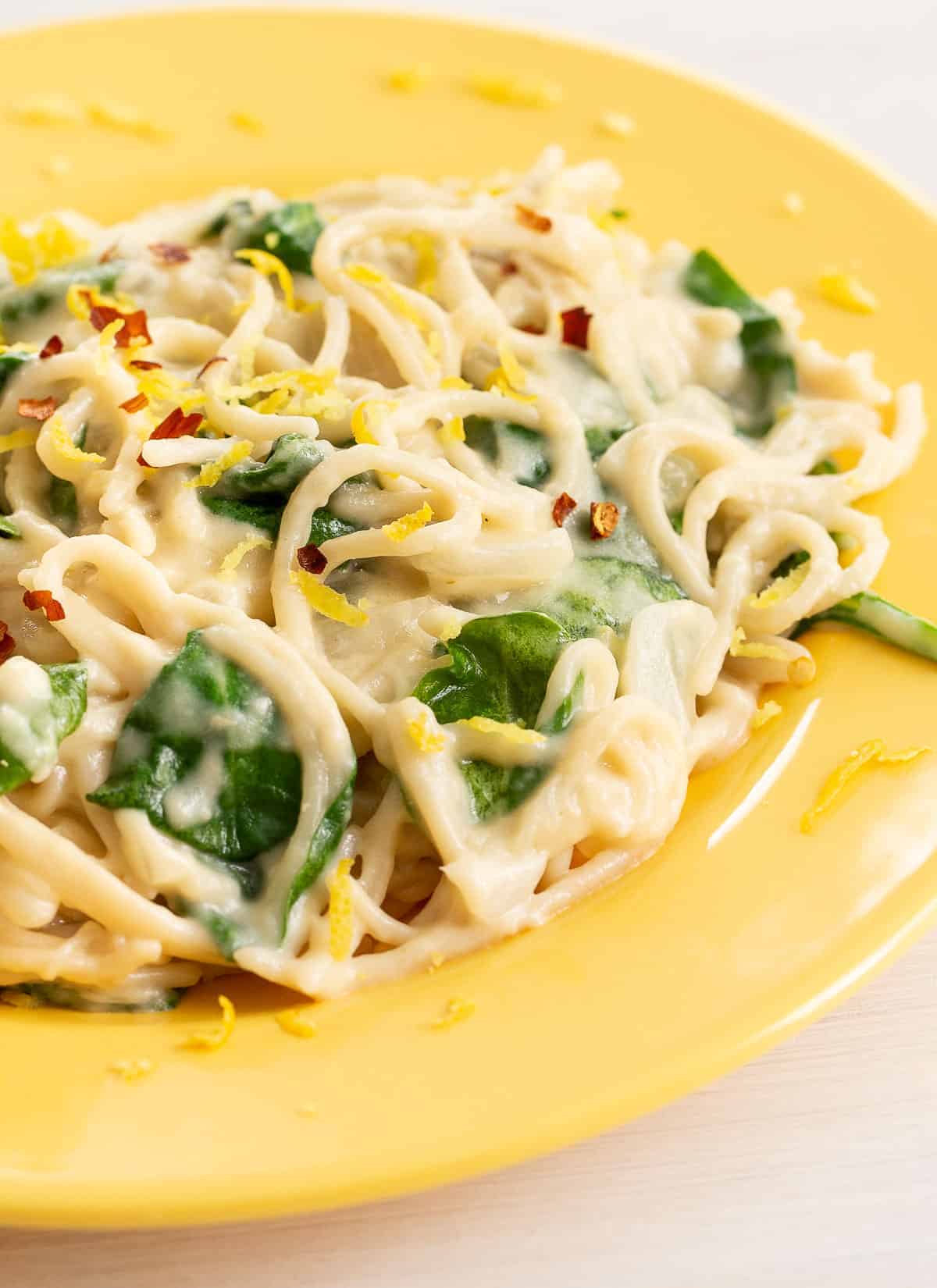 lemon spaghetti with spinach in a yellow bowl.