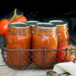 Homemade can tomato soup in quart jars with sealed lids and fresh tomatoes sitting near them