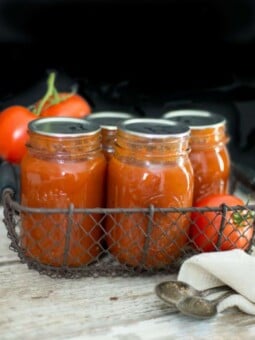Homemade can tomato soup in quart jars with sealed lids and fresh tomatoes sitting near them