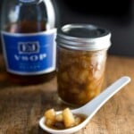 pear compote in a pint jar and a sample of the pears showing on a spoon with Brandy in the background
