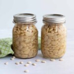canning lima beans in two pint jars with dried beans on table