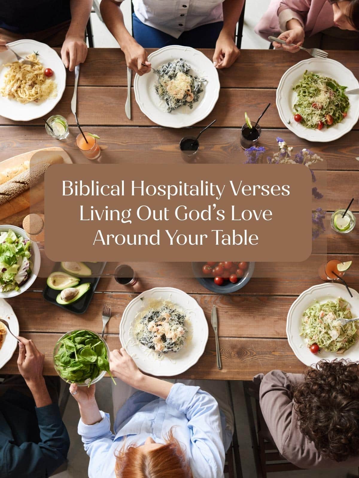 Top-down view of people sharing a meal at a wooden table with pasta, salad, bread, and drinks. Overlaid text reads: “Verses on Hospitality—Living Out God’s Love Around Your Table.”.