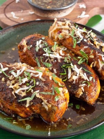 Spicy grilled thai chicken breasts with coconut shreds and sauce on it