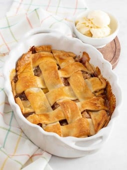Peach cobbler with premade pie crust in an oval baking dish.