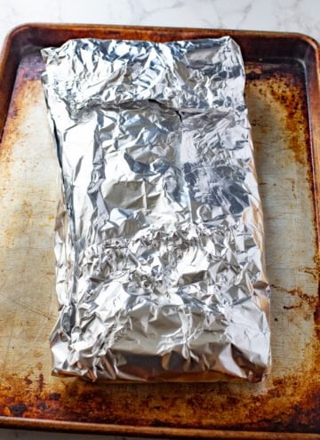 rack of ribs wrapped in foil on a cookie sheet