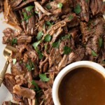 close up of roast beef and a bowl of gravy
