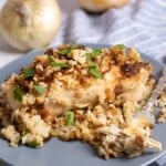 Slow cooker french onion soup mix chicken on a plates with rice and parsely on top. Fork with a piece of shredded chicken on a fork