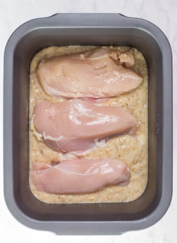 slow cooker pan with 1/2 of the soup mixture and chicken breast on top