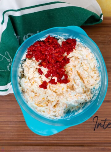 pimento cheese mixed in a bowl with pimentos on top ready to stir in