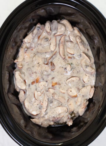 chicken breast in crock pot covered with mushroom sauce before it is cooked