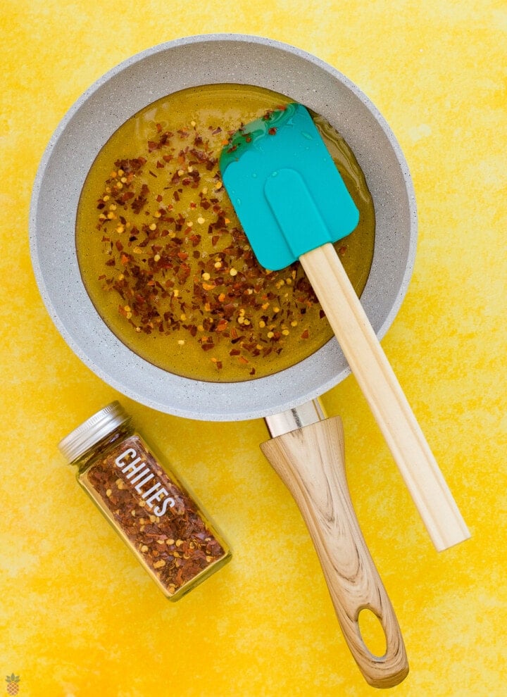 pan of honey stirring in with spatula the red chili flakes and seeds