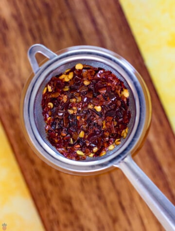 red pepper chili flakes and seeds in a strainer