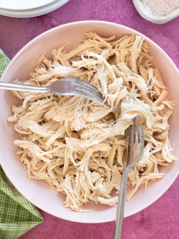 shredded chicken in a bowl with forks pulling it apart