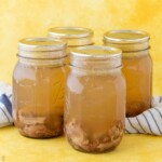 bone broth in pint jars with bits of meat and small oxtail bone