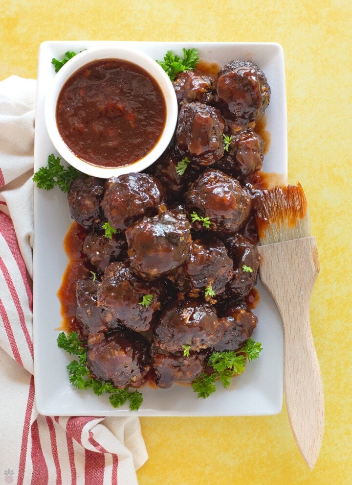bbq meatballs on plate with bowl of sauce and bbq brush