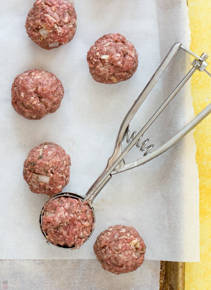 raw meatballs being made with cookie scoop