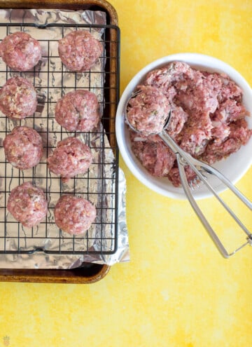 meatballs on baking tray and a bowl of meat with cookie scoop
