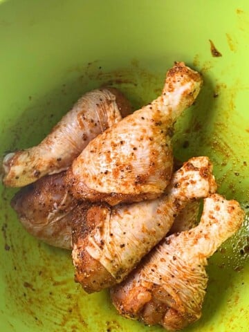 chicken legs coated for going into the air fryer after tossed in bowl