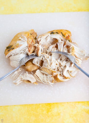 mexican soup chicken on a cutting board being shredded after cooking