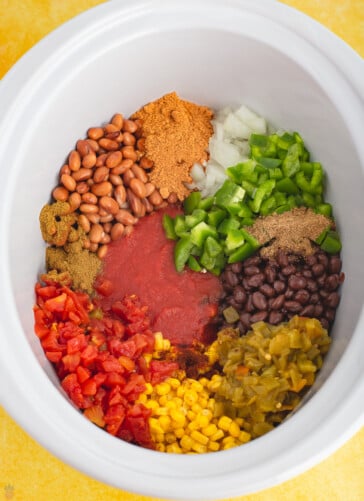 beans, onions, peppers, seasonings and tomatoes in a crock pot for chicken taco soup base.