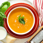 fresh tomato soup with basil as a garnish and a dash of parmesan cheese that uas freshly grated.