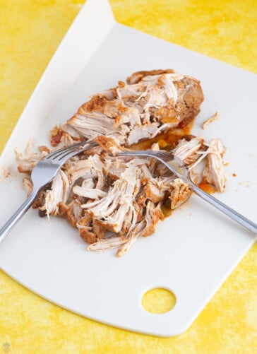chicken for chicken taco soup that is cooked and being shredded with two forks