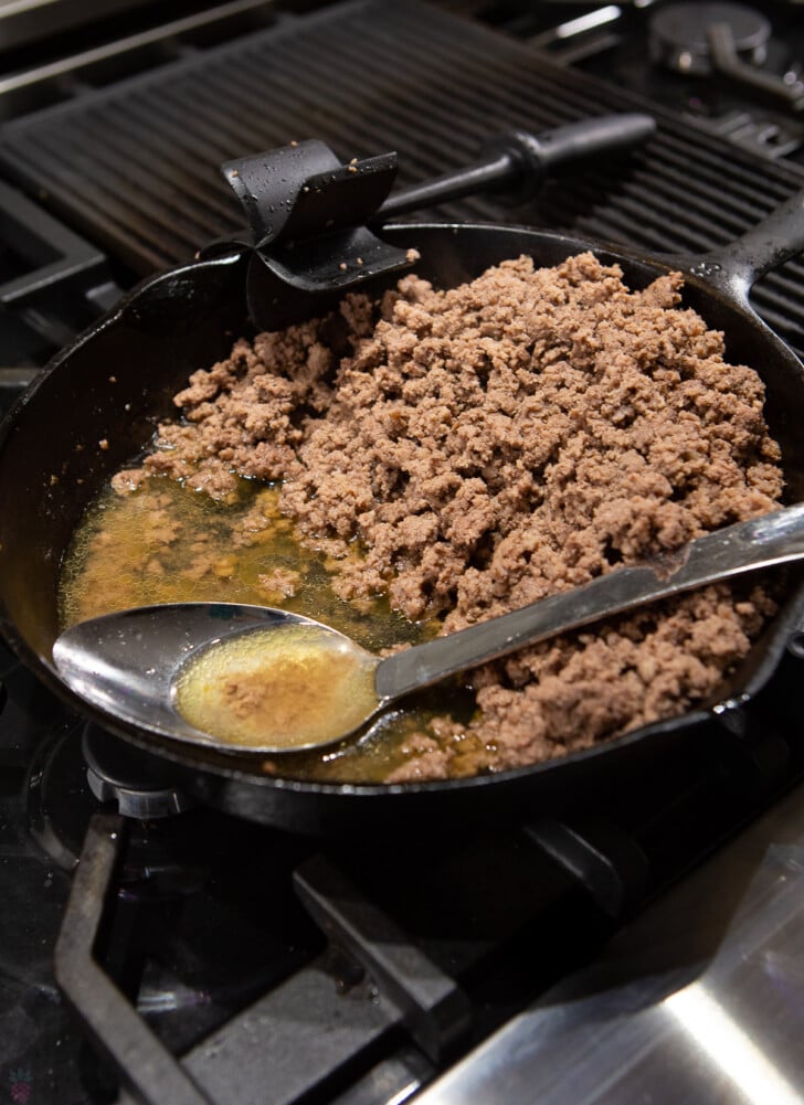 cooked ground beef in black skillet with fat drained to side