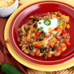 layers of slow cooker mexican casserole ground beef topped with sour cream, fresh jalapeno and cilantro on a plate