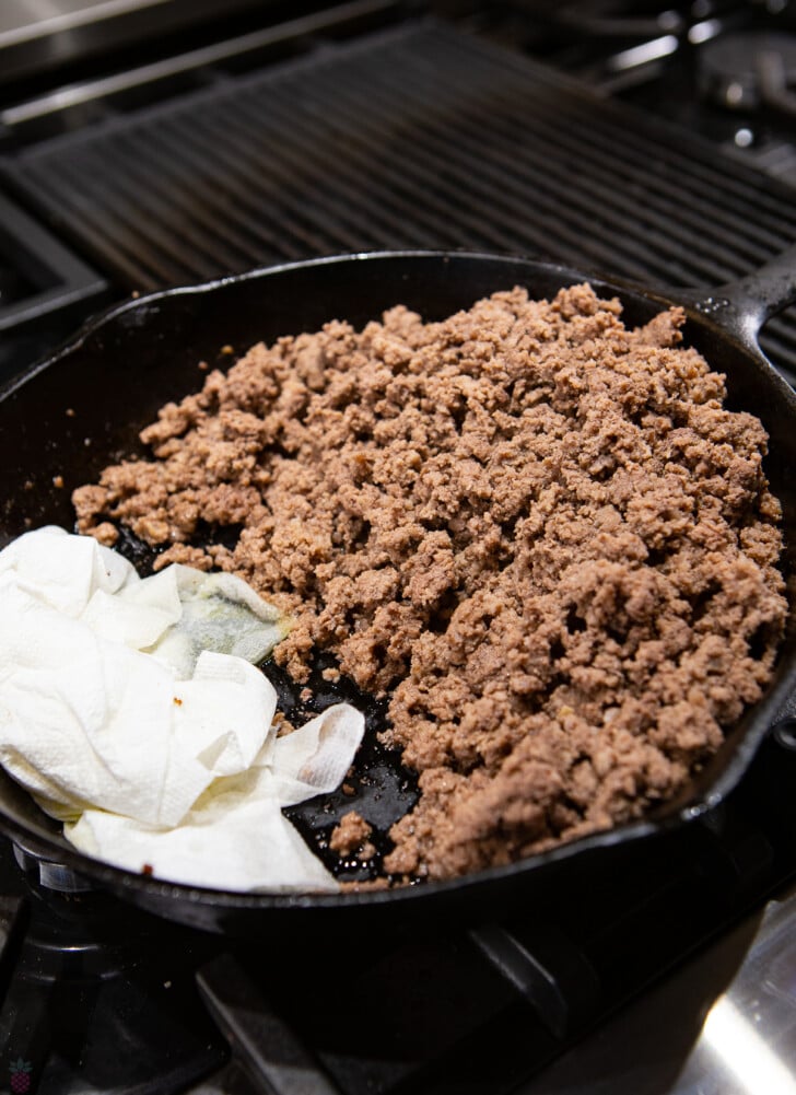 cooked ground beef in skillet with paper towels sopping up grease