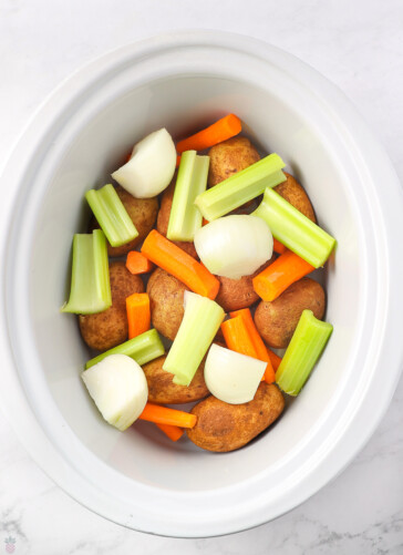 carrots, potatoes, celery, onions, are in slow cooker pot
