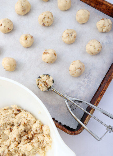 Butterball Cookies dough balls on cookie sheet and cookie scoop making them into balls
