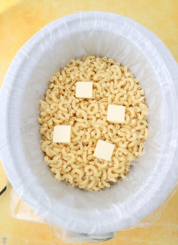 cooked macaroni in a crock pot with butter on top