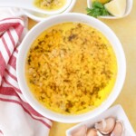 Lemon garlic butter sauce in a bowl with fresh garlic lemons and parsley sitting beside it