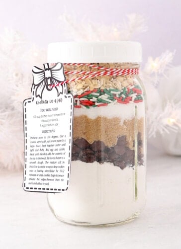 cookie in a jar mix with gift tag on it. Layers of flour chocolate chips two kinds of sugar sprinkles and oatmeal
