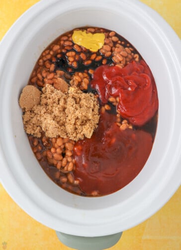 boston baked beans with seasonings, brown sugar and ketchup in a crock pot ready to be cooked