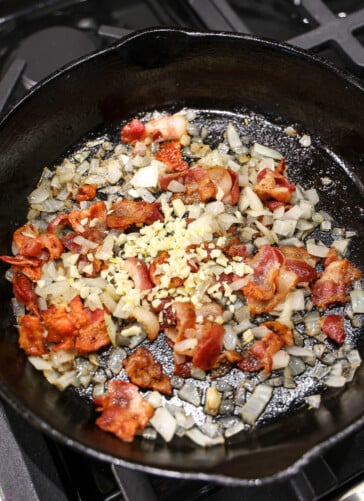 bacon, onions, garlic sizzling in a black skillet