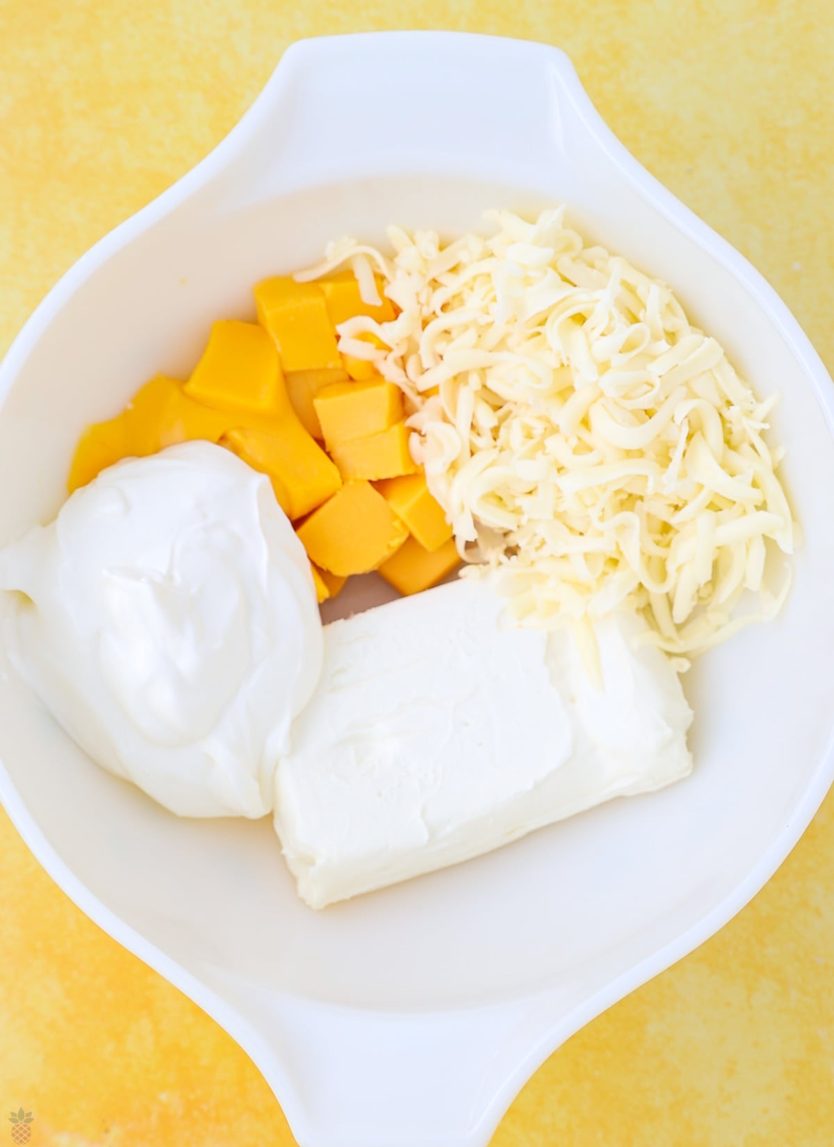 A bowl with soft cream cheese Velveeta mozzarella and sour cream