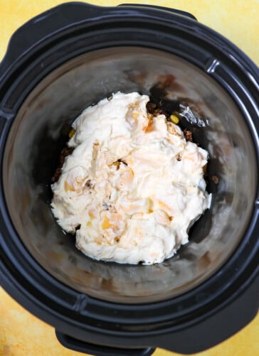 Layering cheese mixture on top of ground beef for taco dip in a crock pot