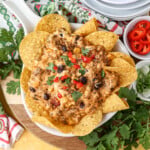 Taco dip on tortilla shells with cilantro jalapenos and onions on top