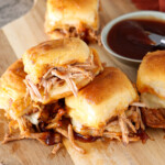 Hot pulled pork slider with extra sauce and a bowl next to them