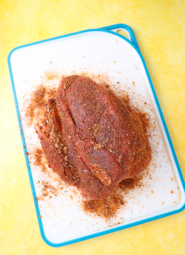 Shoulder on a cutting board with barbecue dry rub all over it