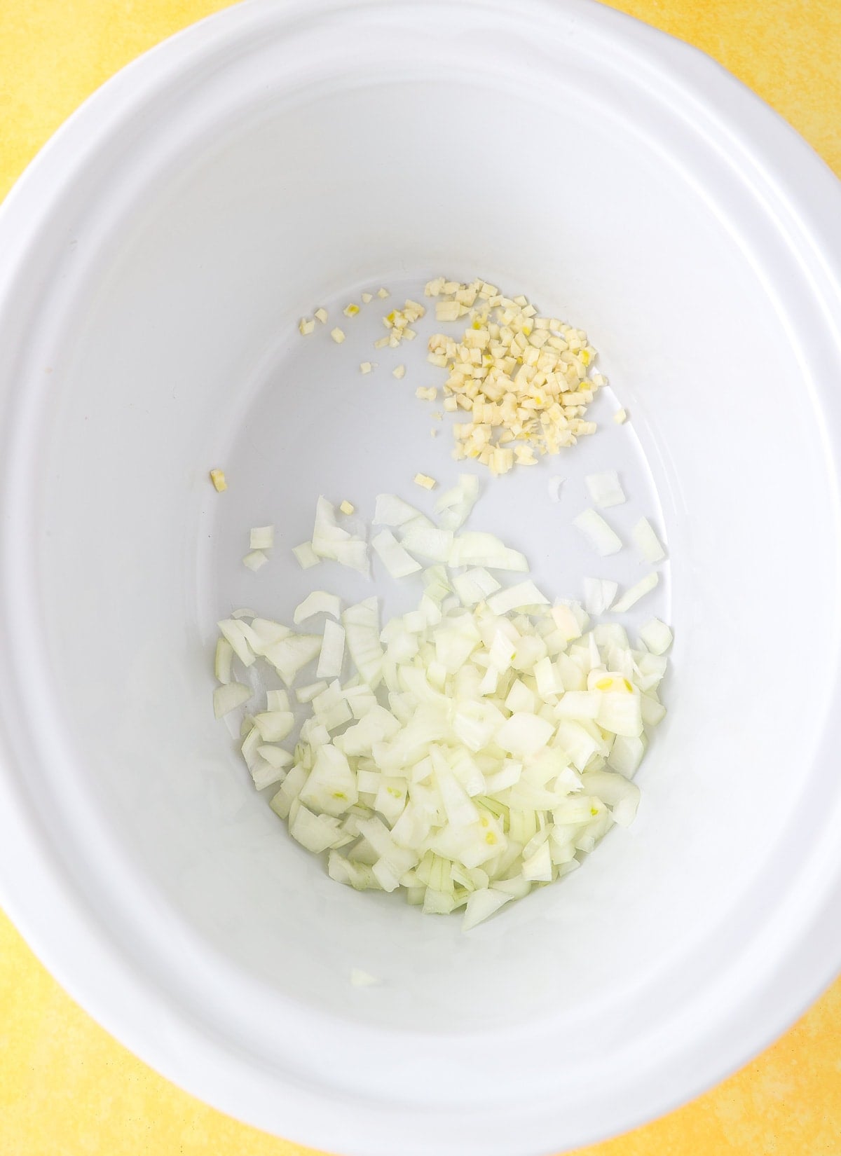 Slow cooker Liner filled with chopped onions and chopped garlic