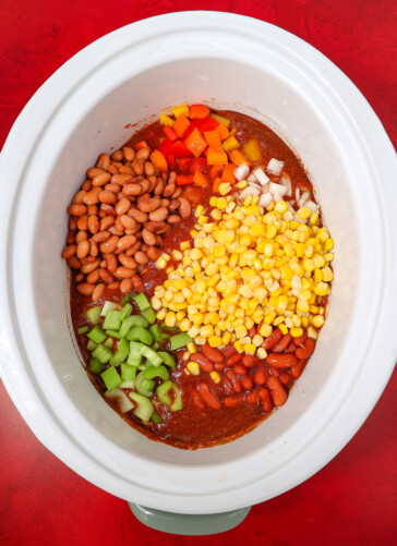 Vegetables being added to taco soup beans Peppers corn celery and onions