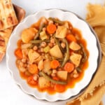 Instant pot vegetable stew in a bowl with a big slice of bread beside it