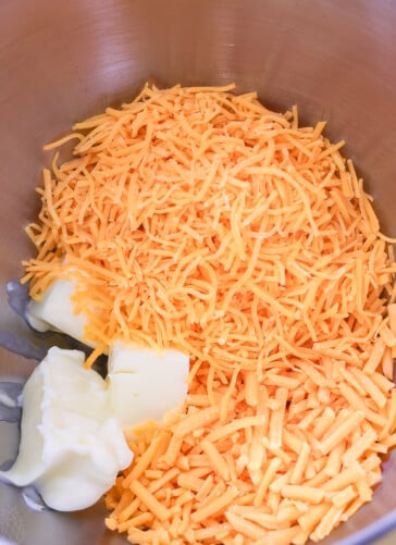 Sharp cheddar cheese and extra sharp cheddar cheese and butter in a bowl