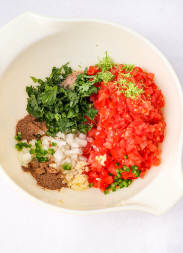 Salsa Fresca ingredients in a bowl chopped tomatoes zest lines cilantro seasonings onion garlic and jalapenos