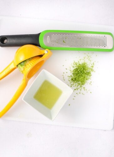 A line being squeezed for juice and a zester that has graded lime skin for zest