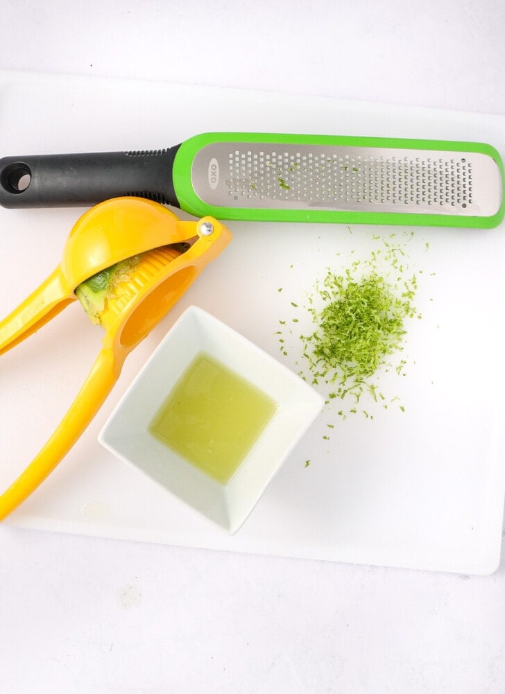A line being squeezed for juice and a zester that has graded lime skin for zest